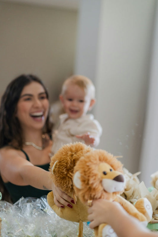 A woman holding a teddy bear in front of a baby