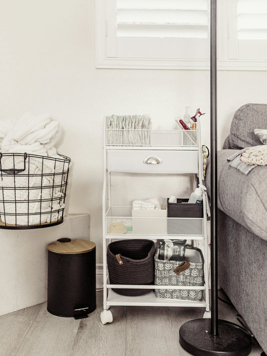 White rolling cart filled with baby supplies and baskets.